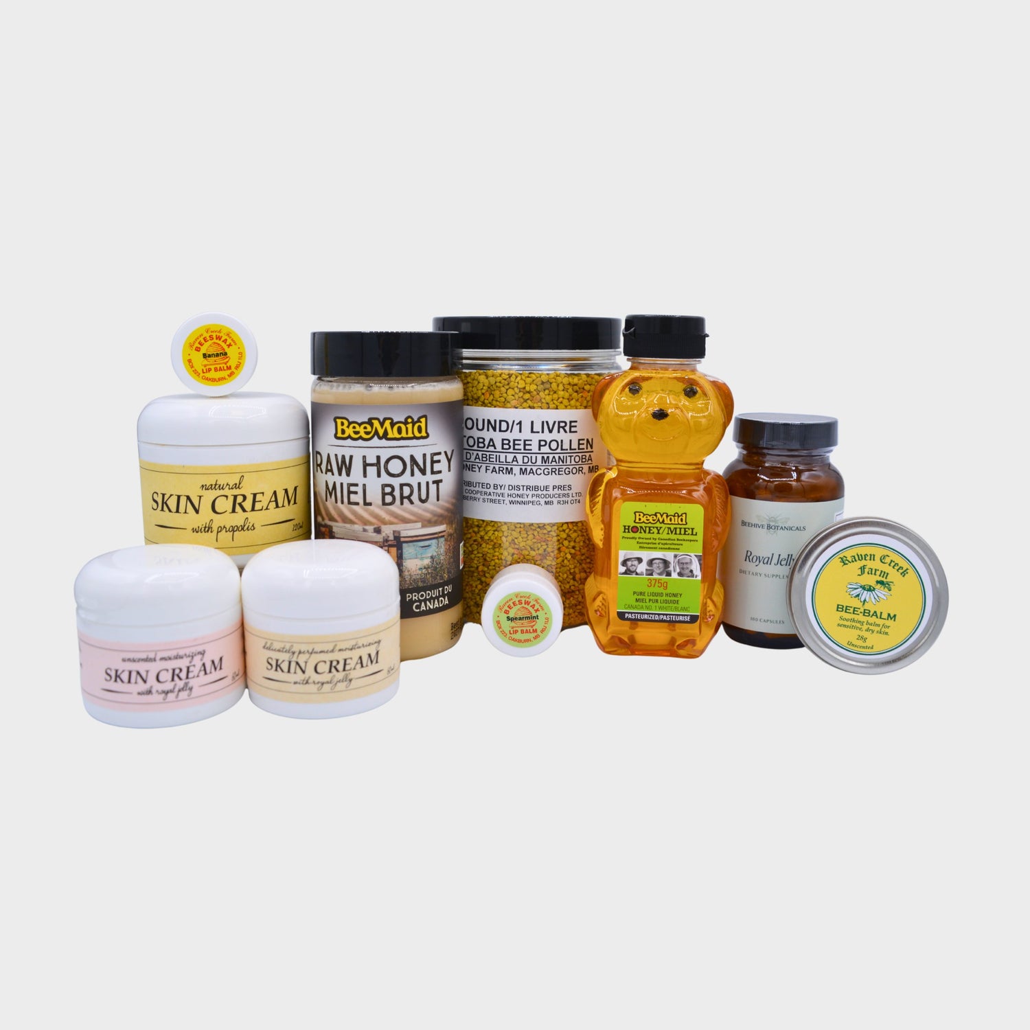 A collage of products that are produced from the hive, including propolis skin cream, a jar of bee pollen, and a bottle of raw honey on a white background