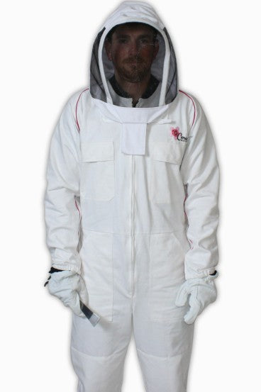 A person wearing a full white beekeeping suit with a zippered front, long sleeves, and attached gloves. The suit includes a hood with a black mesh veil covering the face for protection. The person is standing and looking forward, and the suit has a small embroidered logo on the left chest.