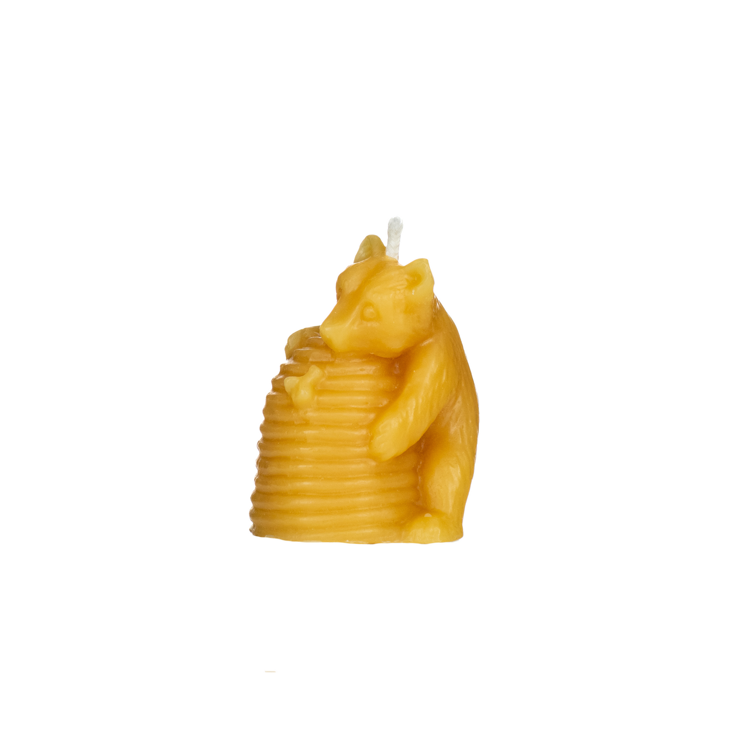 A small, yellow beeswax candle shaped like a bear hugging a beehive on a white background