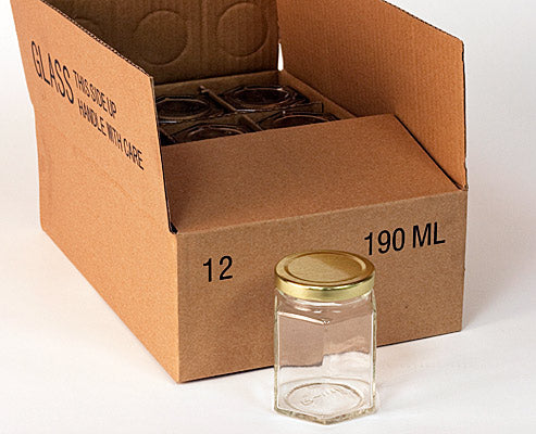Clear 190mL glass hexagonal jar in front of a cardboard box containing a case of 12 on a white background