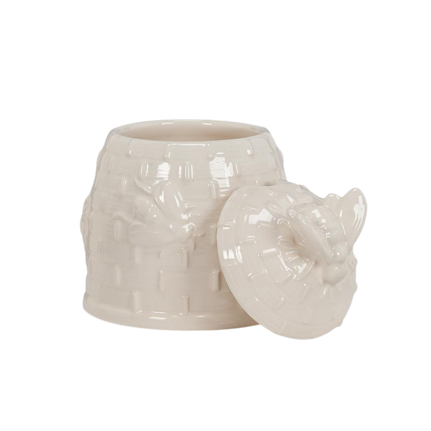 A white beehive covered pot with its lid resting against its right side on a white background