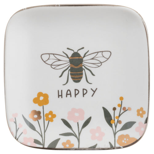 A square ceramic trinket tray with a floral pattern and a bee illustration in the center, with the word 'HAPPY' below it on a white background