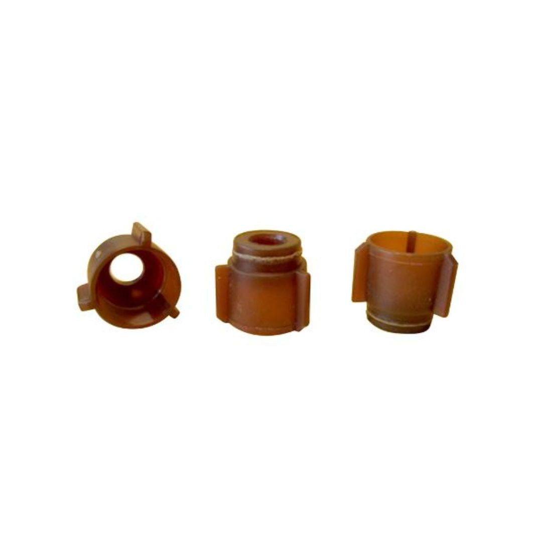 Three brown plastic cell plugs designed for use in a Jenter Comb box to mark designated spots for queen bees to lay eggs, on a white background