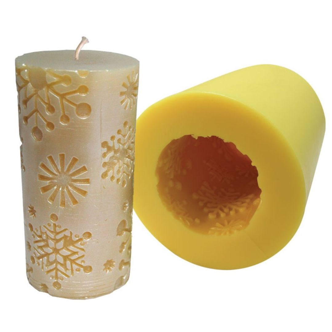 Yellow snowflake candle mold with snowflake shapes inside and yellow candle with snowflake shaped indents as design on a white background