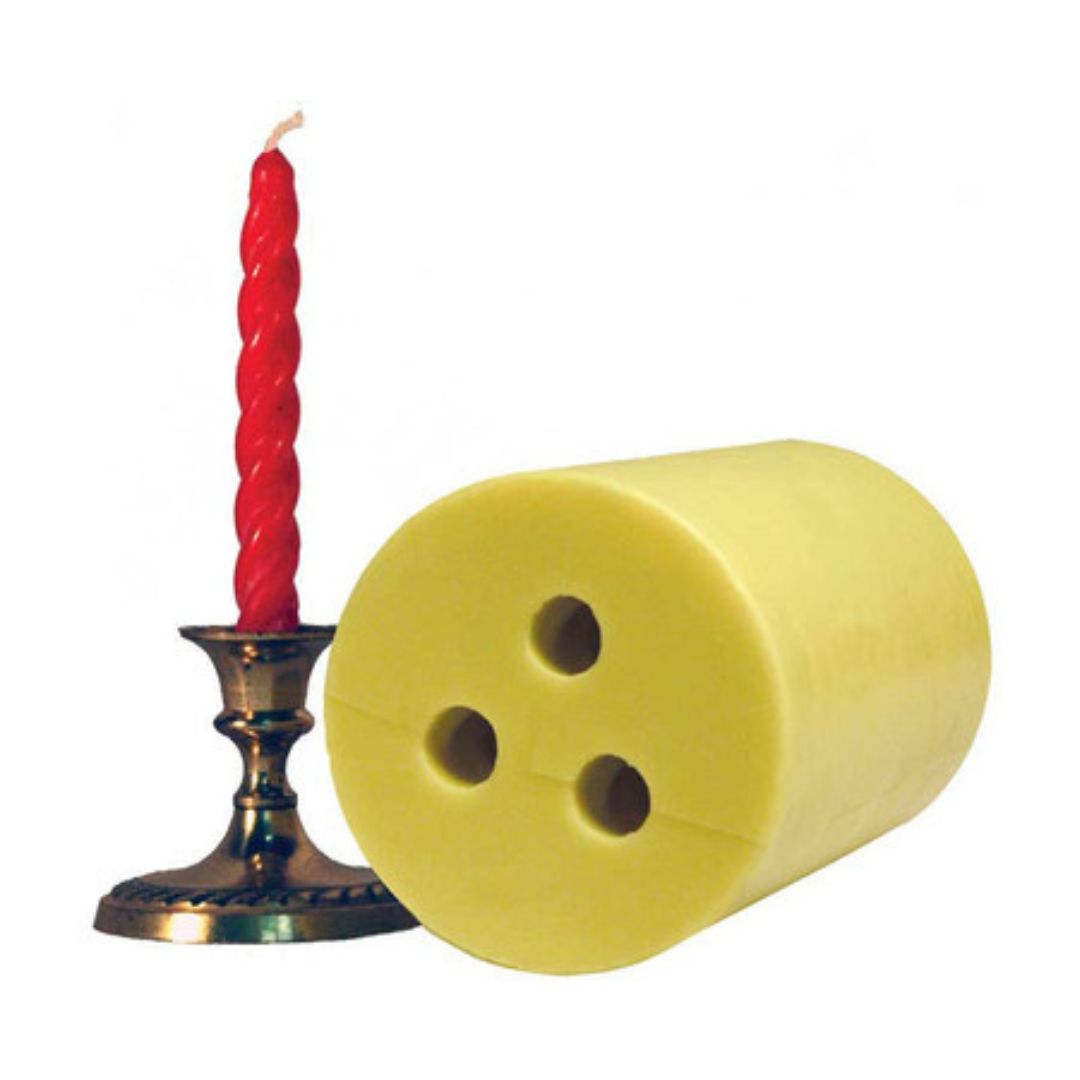 A yellow circular spiral candle mold with 3 spiral circle holes and a red spiralled candle in a candle holder on a white background