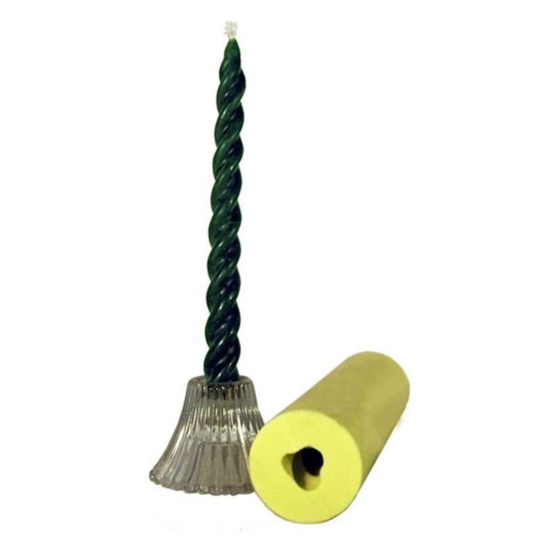 A green spiral candle stands upright in a clear, ribbed glass holder beside a yellow candle mold on a white background