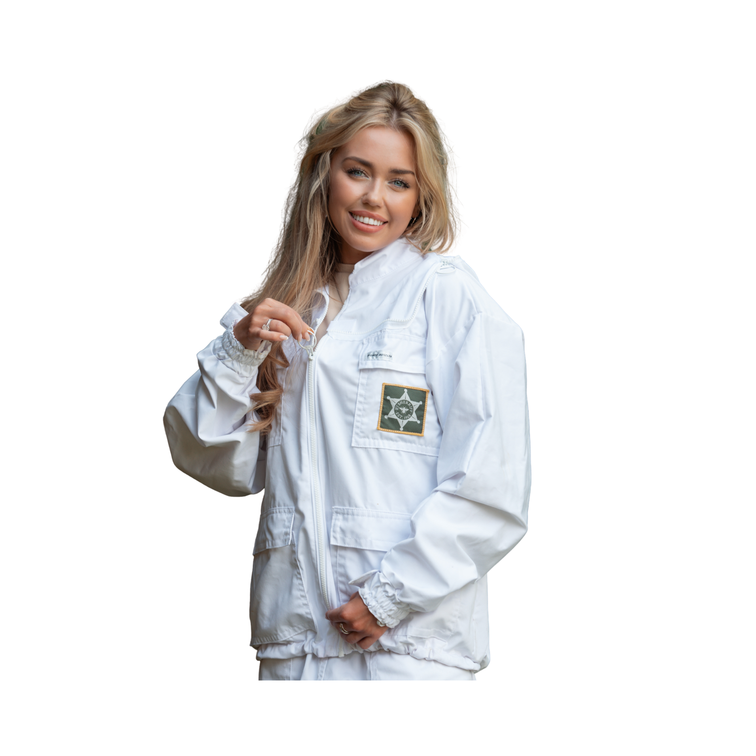 A woman wearing a white utility jacket with a green and gold patch on the chest pocket, posed against a solid white background.