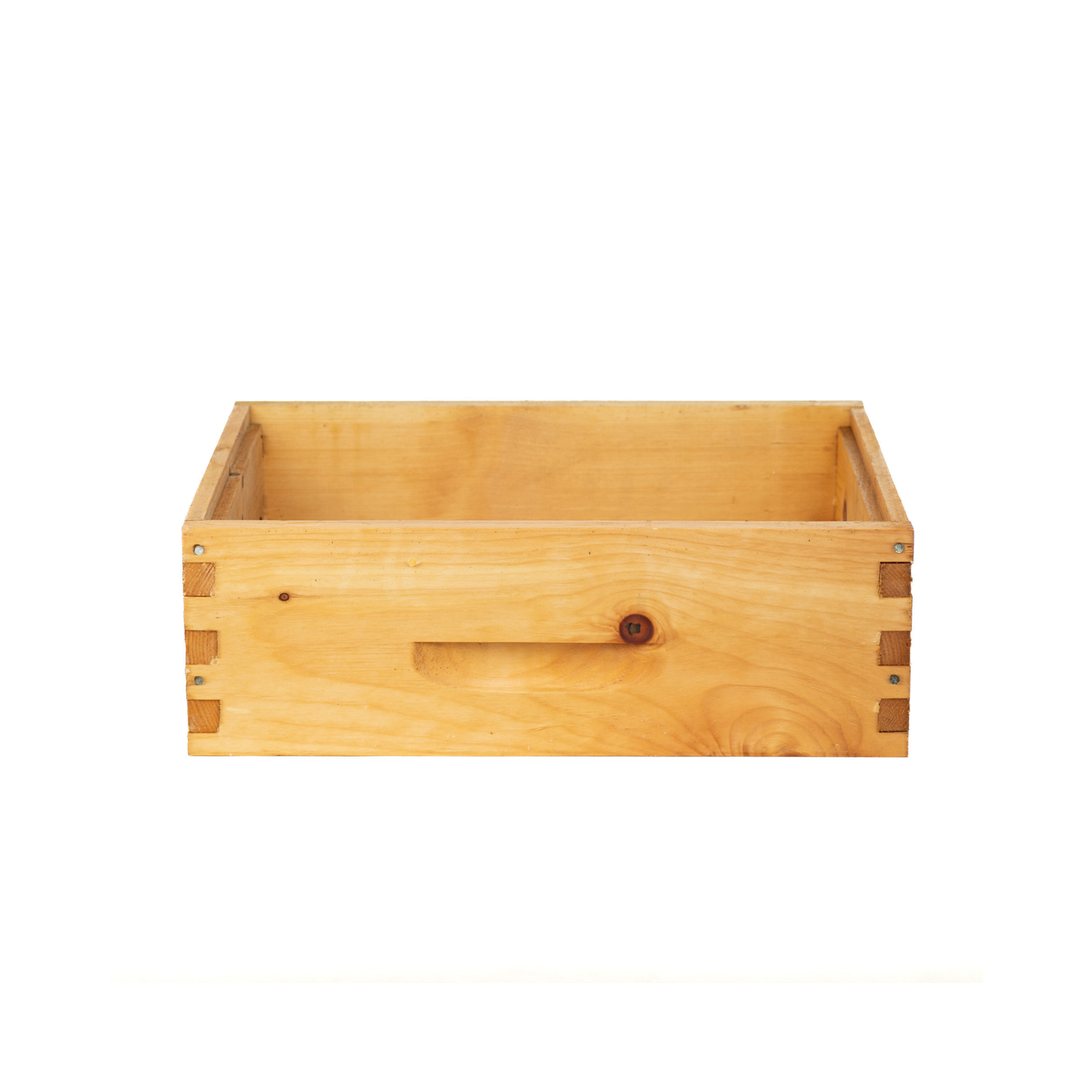 A wooden bee super box used in beekeeping. It is rectangular, open at the top, and made from smooth light-colored wood with finger-jointed corners and a carved handhold on the side on a white background.