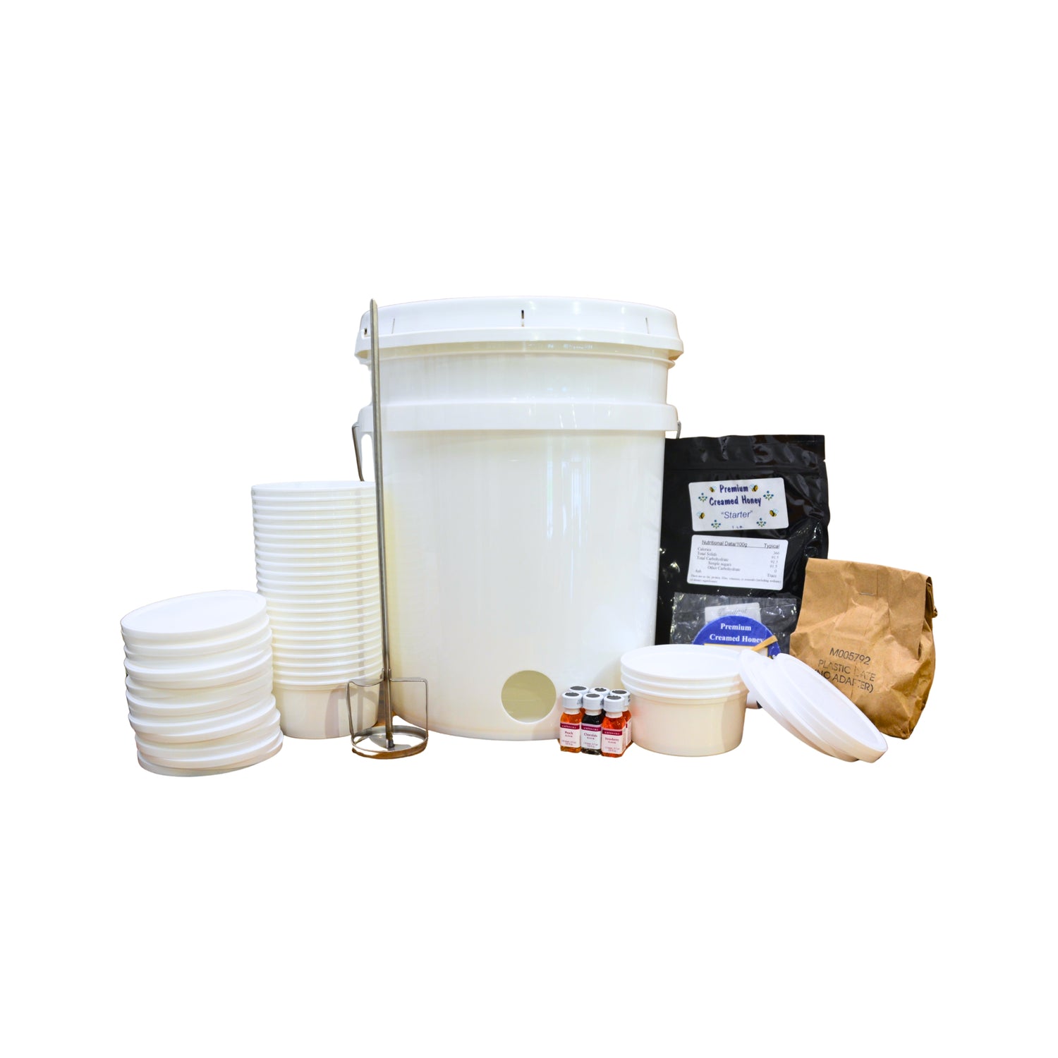 A white plastic creamer bucket kit with a lid, glass stirring rod, plastic lids, small bottles, a jar, and bags of ingredients on a plain white background.