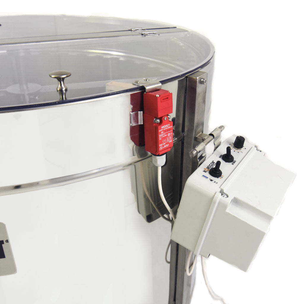 A close up of a metal, radial motorized honey extractor with capacity for 28 frames, branded KONIGIN, on stands with a control switch emphasized on a white background