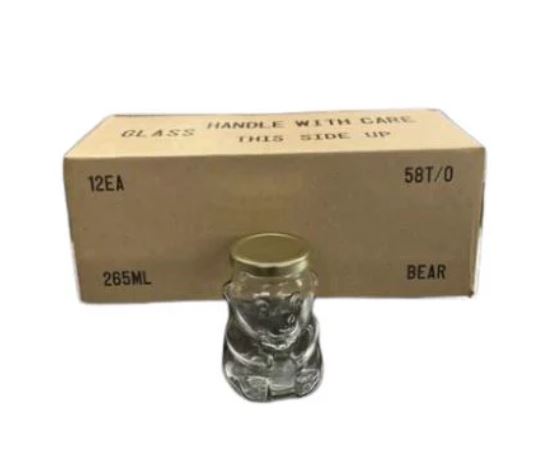 A clear 265mL glass bear-shaped container with gold lid in front of a cardboard box containing 12 jars