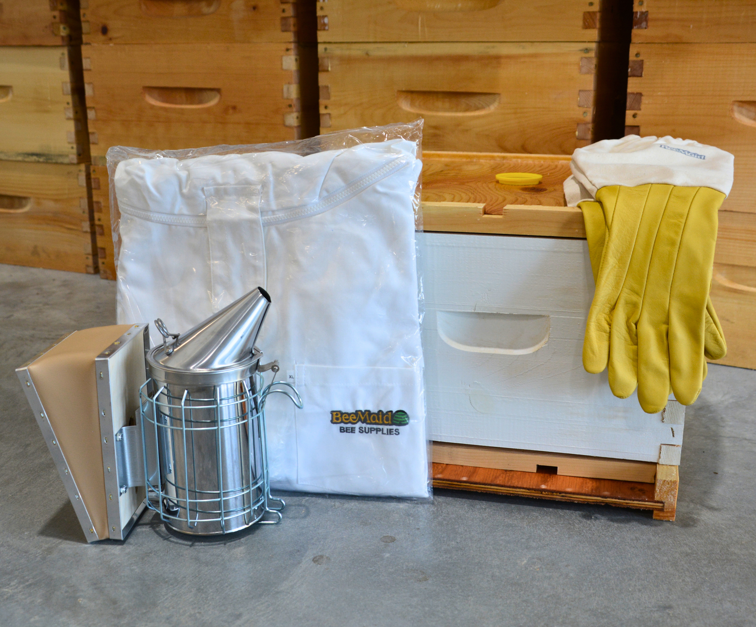 A collage of the Bee Maid Bee Supplies Beekeeping Starter Kit with a pair of cowhide gloves, a beekeeping jacket, and a smoker
