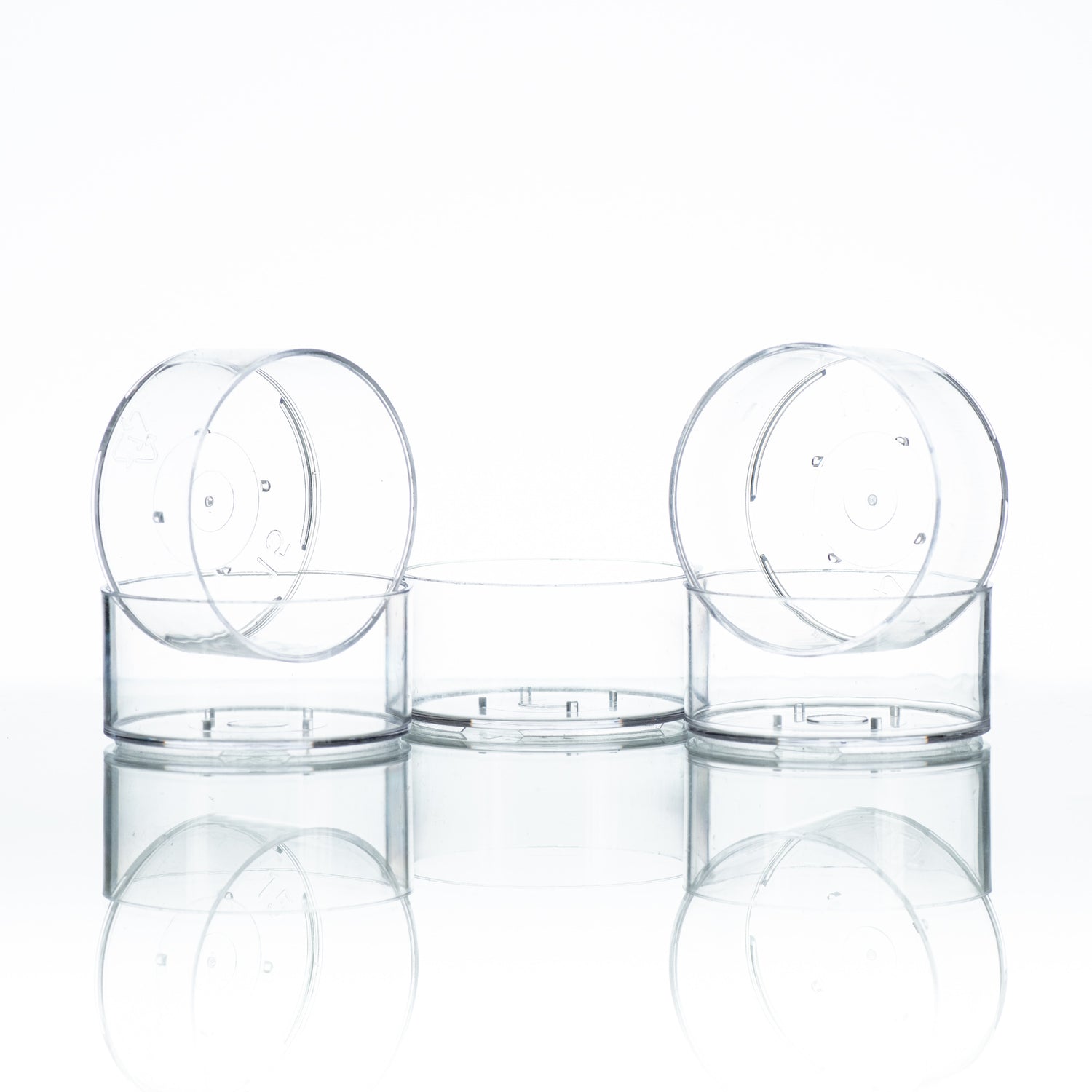 Five clear plastic tealight cups, designed for candle making on a white background