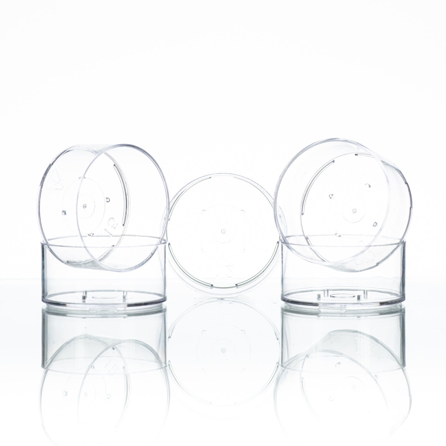 Five clear plastic tealight cups, designed for candle making on a white background