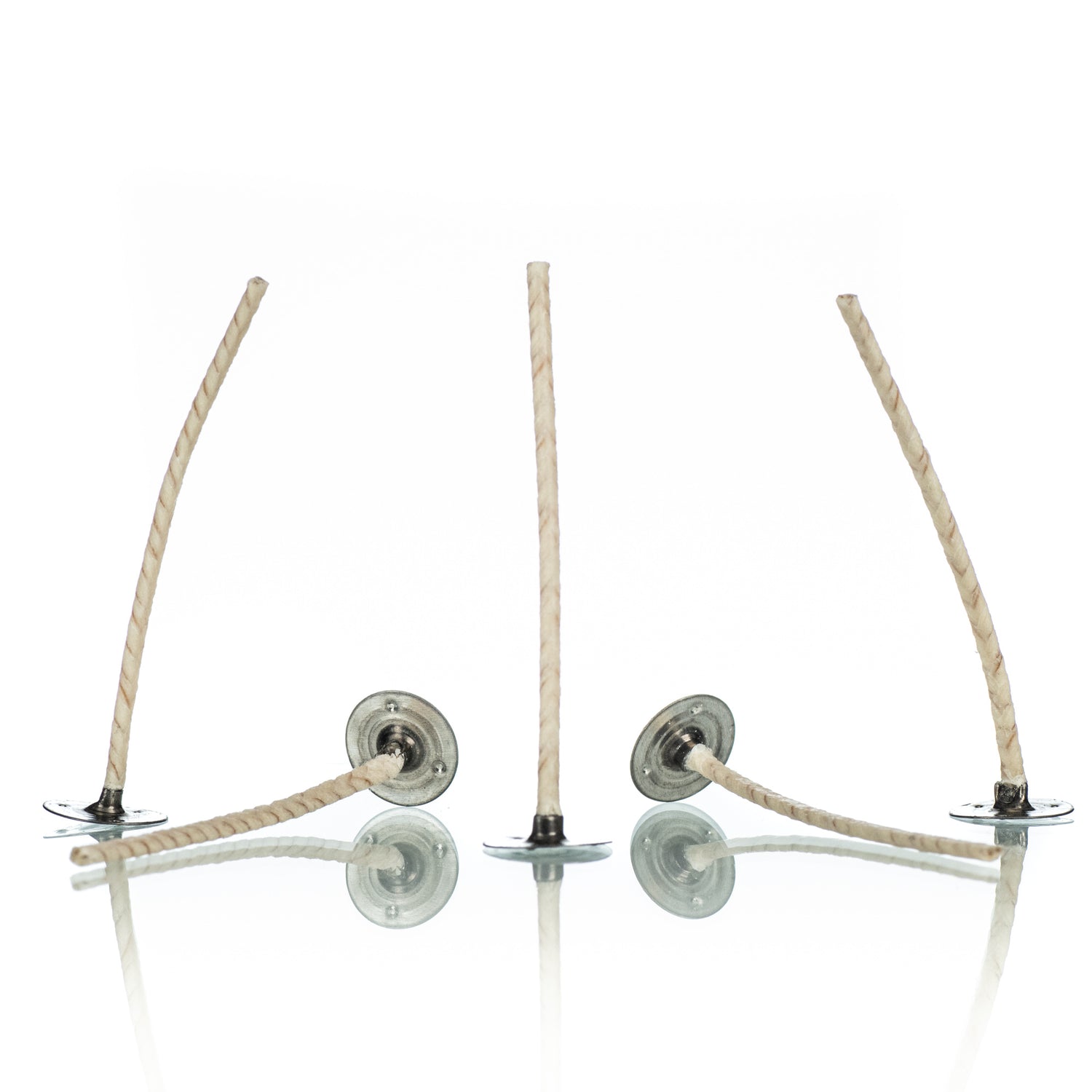 Five white candle wicks attached to silver wick tabs on a white background