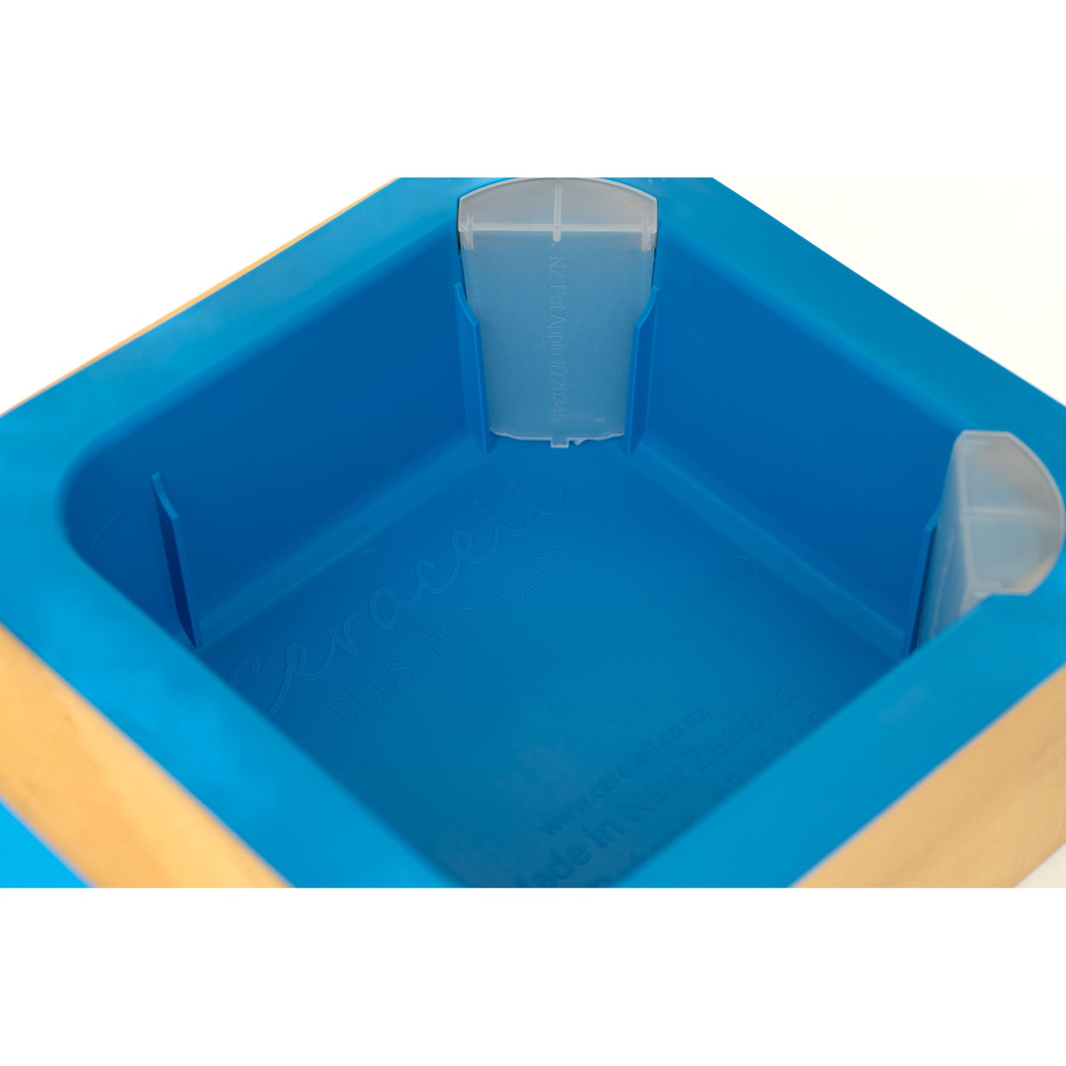 Close up of a blue top feeder with a patented corner access system, accompanied by corner caps and a chimney, displayed alongside a wooden frame.