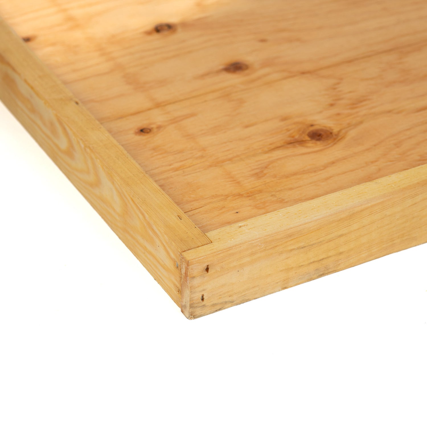 A close up of a wax-dipped wooden hive bottom board.