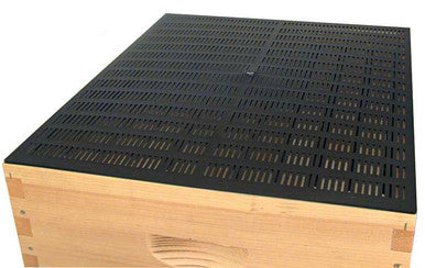 A propolis collecting mat resting on top of a super on a white background