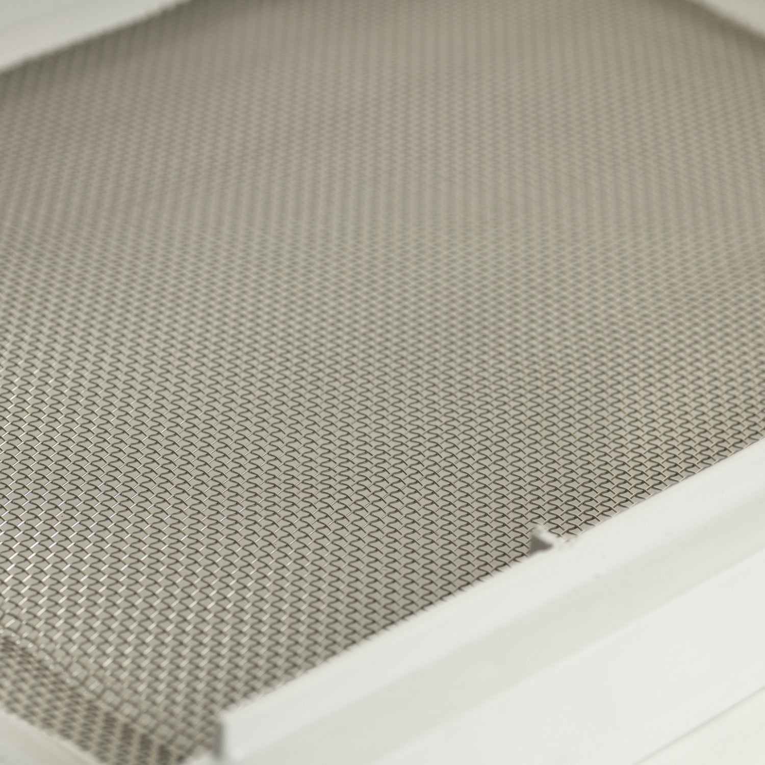 A close up view of a white rectangular Varroa-Nator Screen Insert with a stainless steel screen and molded plastic frame.