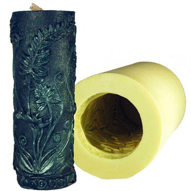 A yellow cylinder candle mold with fern designs and a green cylinder candle with a fern design on a white background