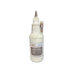 A white plastic bee care spray bottle with a pointed metal nozzle and a small attached tube, wrapped in clear plastic and labeled 'APICARE NATURAL BEE CARE'.