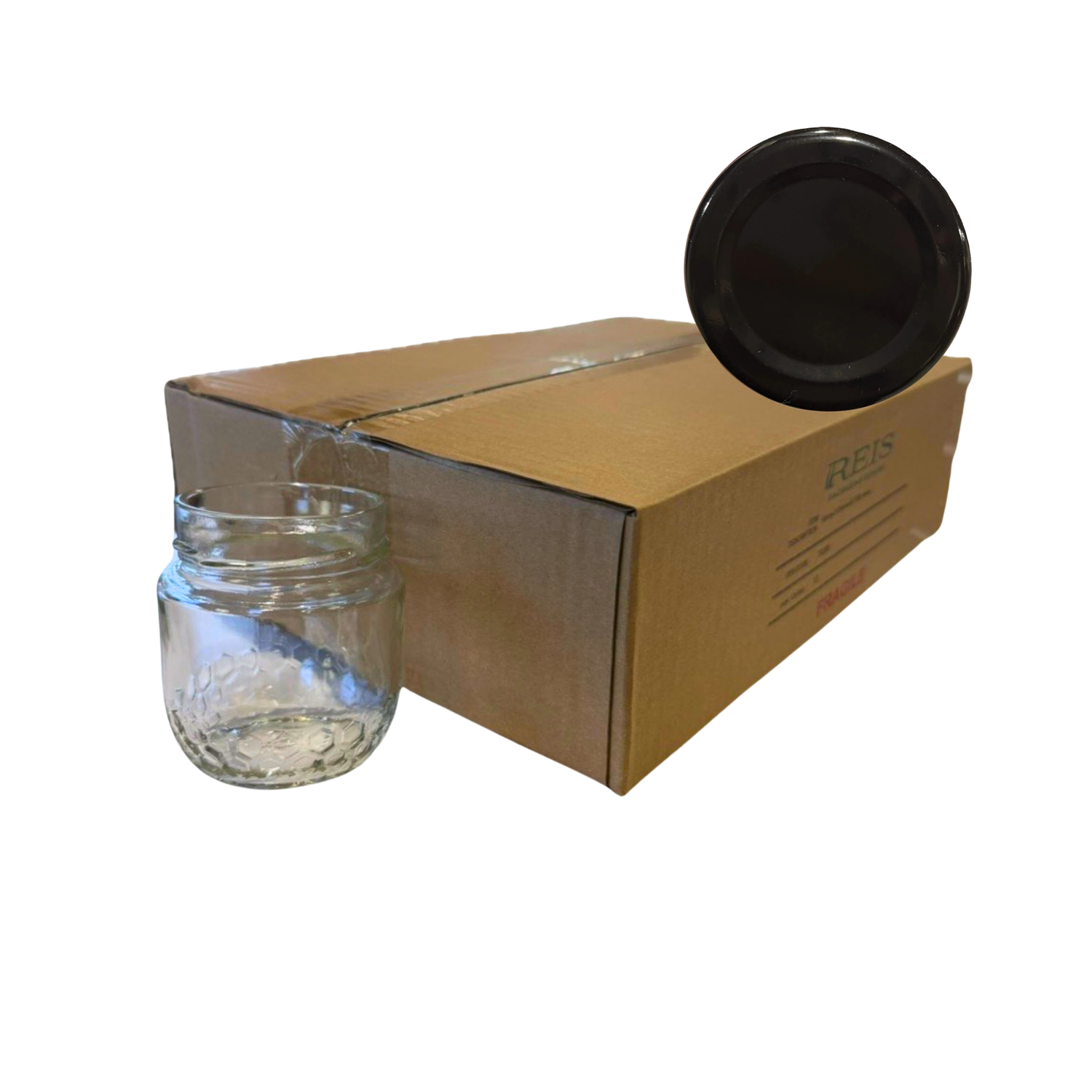 A clear glass jar shown next to a brown cardboard box, with a black lid resting on top of the box, isolated on a white background.