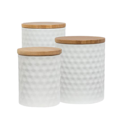 Three white textured ceramic canisters with wooden lids on a white background
