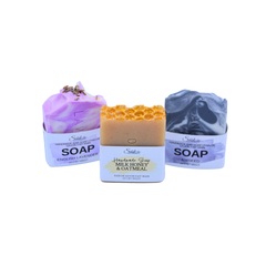 Three bars of handmade soap displayed side-by-side on a white background. The left bar is lavender English Lavender, the center bar is golden-brown Milk Honey & Oatmeal, and the right bar is aniseed. 