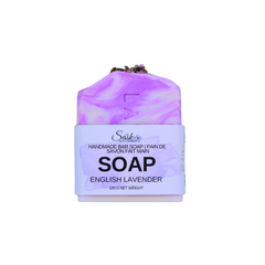 A bar of handmade soap wrapped in a white paper label that reads 'English Lavender SOAP'. The soap itself has a marbled purple and white pattern, and a small sprig of lavender is tucked on top.