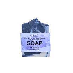 A handmade bar of soap with a dark blue-gray and white marbled pattern, wrapped in a white paper label that reads 'Handmade Bar Soap SOAP Aniseed'.