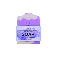 A handmade bar of soap labeled 'Saskatoon Berry', featuring a purple and cream marbled design with a white paper band around the middle on a white background