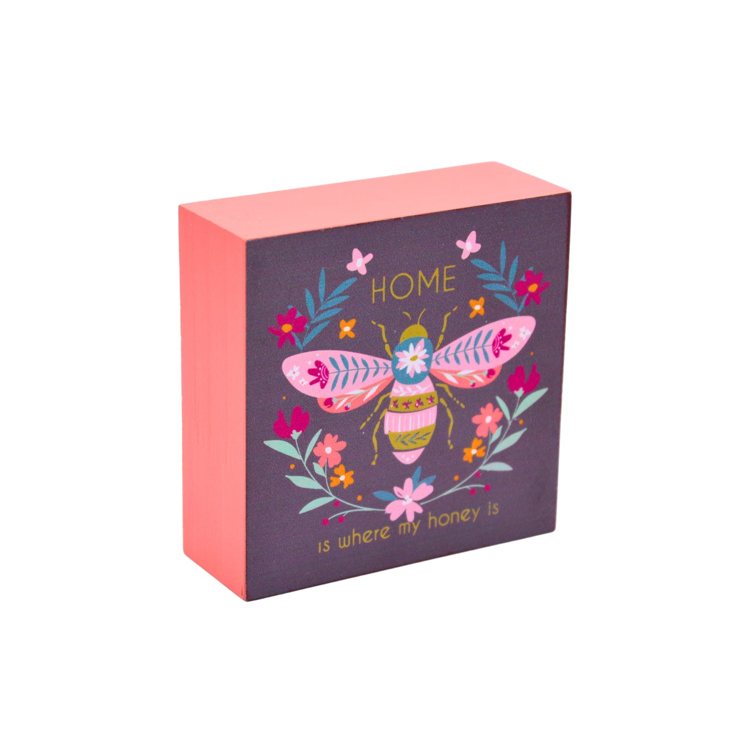A square decorative gift box with a coral pink side and a dark purple front panel featuring a colorful illustrated bee, flowers, butterflies, and the words “HOME is where my honey is.”.