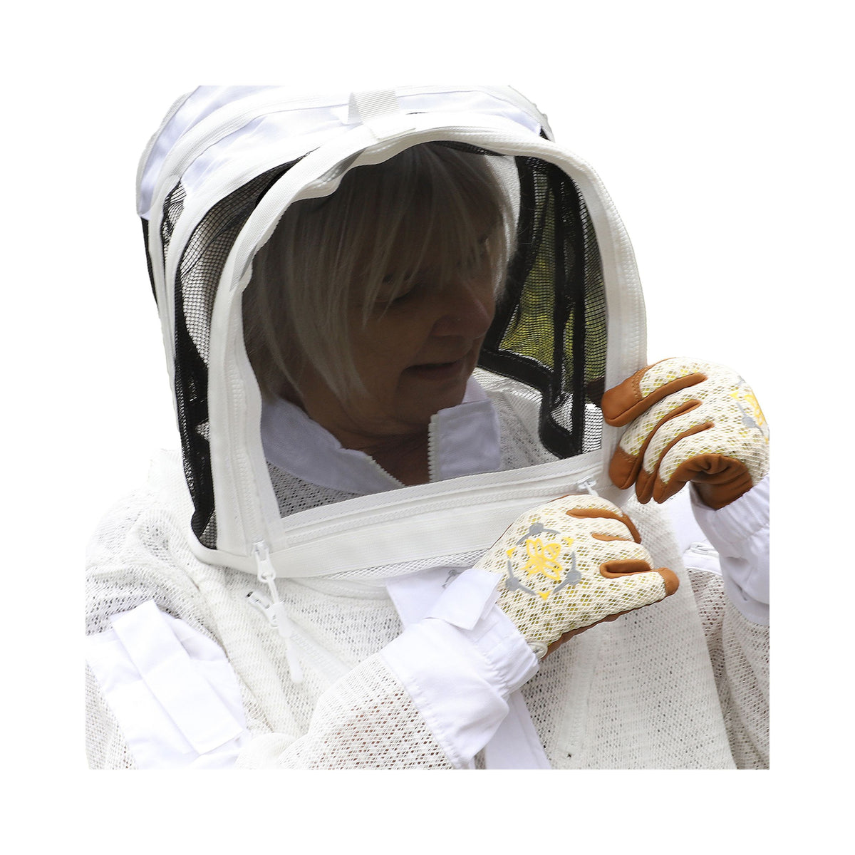 A woman adjusting the zipper on her beekeeping veil while wearing a beekeeping suit and gloves on a white background