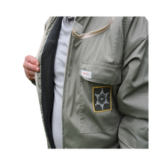 Close-up of a person wearing a khaki BeePro suit over a white shirt, with a black mesh lining visible at the open chest pocket and a small embroidered badge on a white background