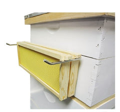 Example of the metal frame holder sitting over the edge of the hive body and supporting frames. 